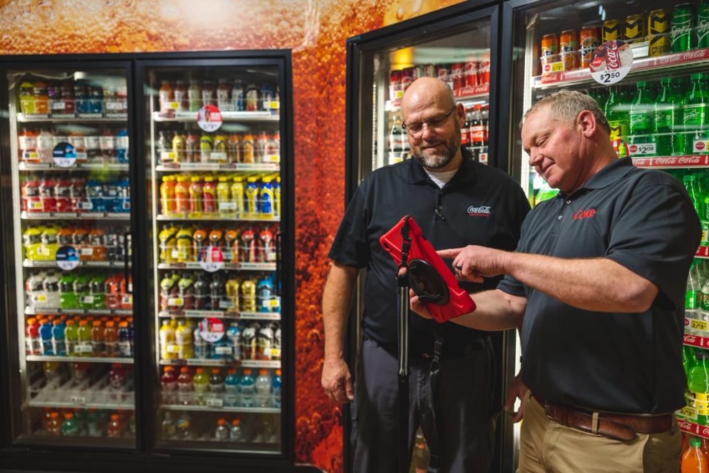 Two people standing in front of coca-cola cooler
