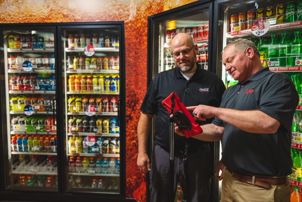 Two people standing in front of coca-cola cooler